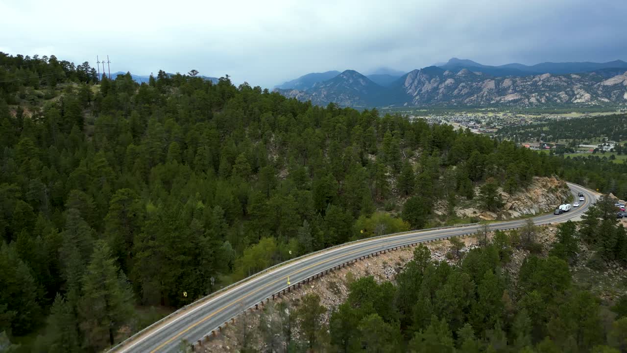 volar sobre la carretera asfaltada y las montañas boscosas cerca del parque estes en el norte de colorado, estados unidos