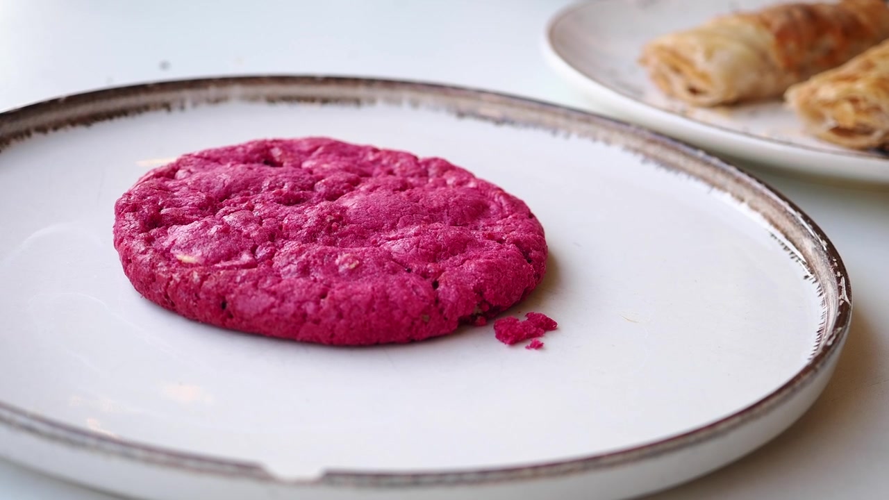 Hand Removes Vibrant Pink Cookie from White Plate