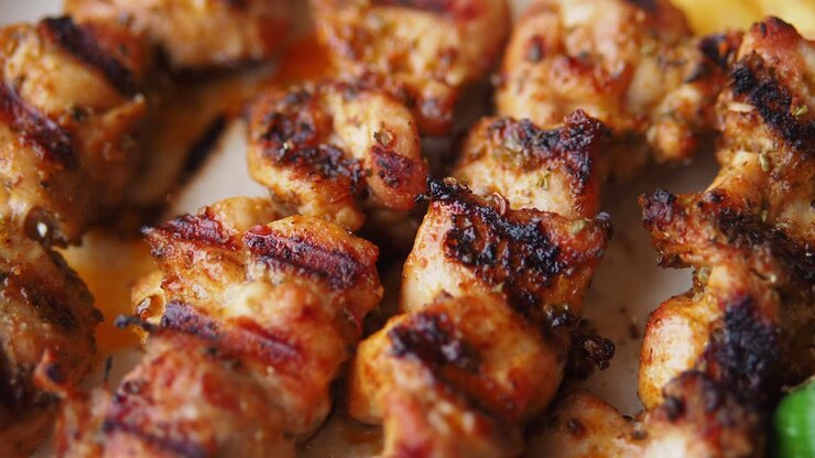 Primo piano di deliziosi spiedini di pollo alla griglia con patatine fritte e peperoni