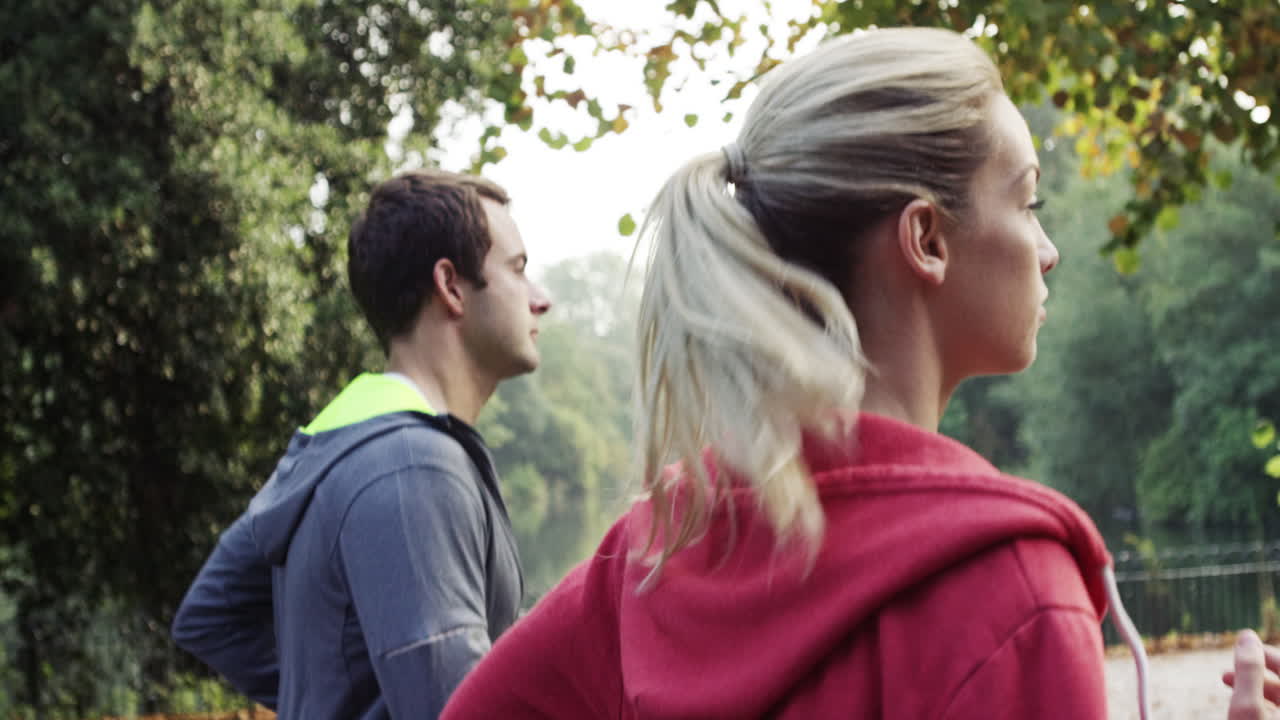 웨어러블 기술과 연결된 장치를 착용한 공원에서 달리는 운동 부부