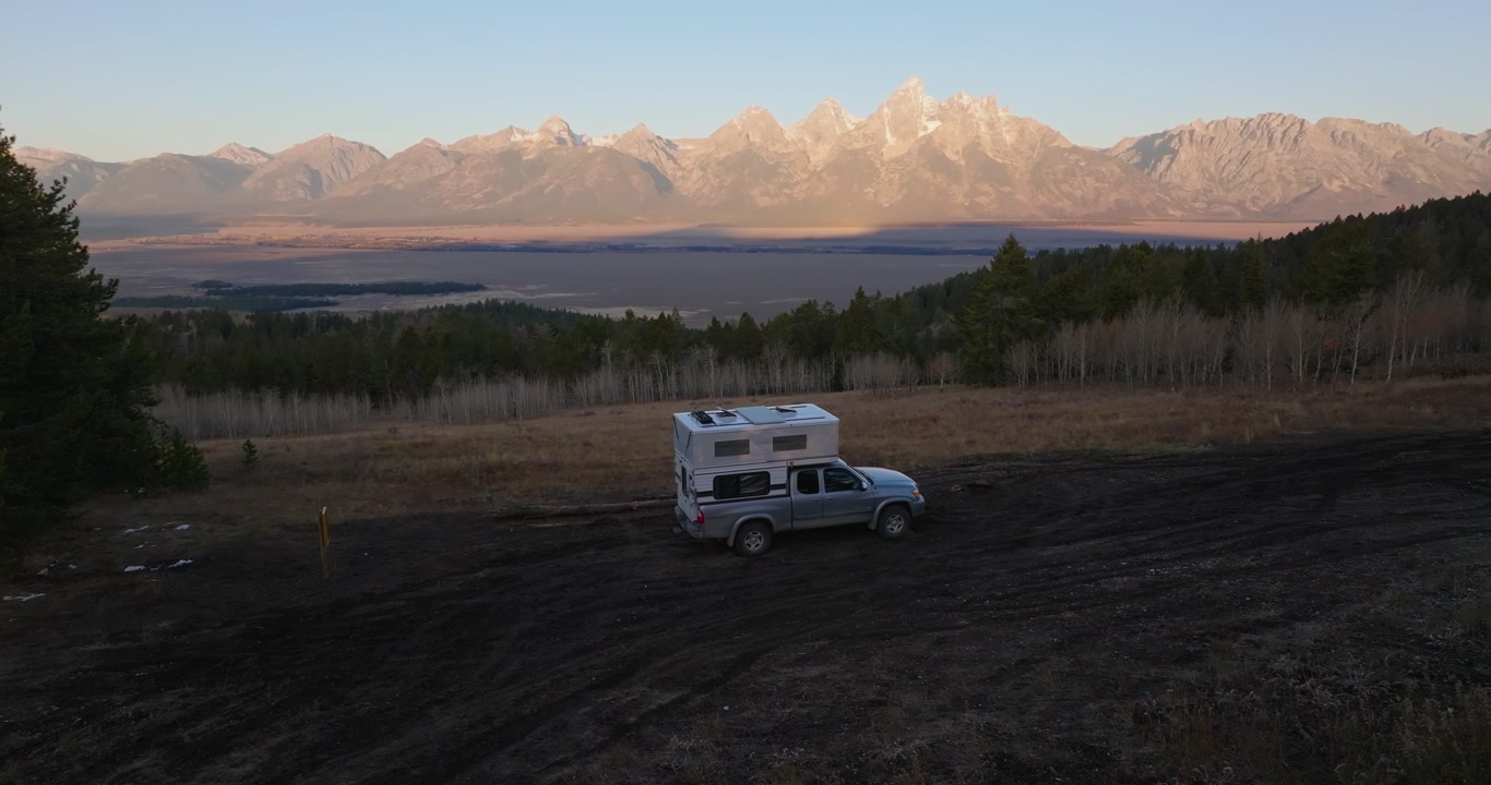 Camper parked in open valley with Grand Teton mountains with alpenglow light