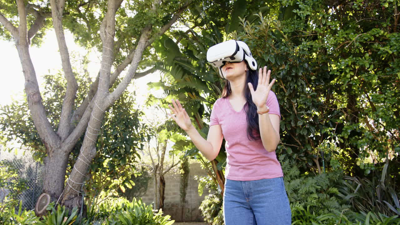 Donna in piedi all'aperto, con un visore VR, circondata da una vegetazione lussureggiante.