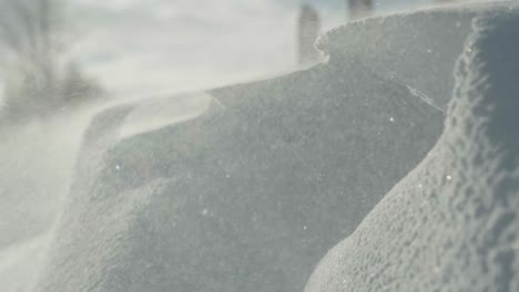 Primer-Plano-De-Una-Acumulación-De-Nieve-Mientras-El-Viento-Arrastra-Partículas-De-Hielo-Por-El-Marco,-Revelando-Arcoíris-Por-Refracción.