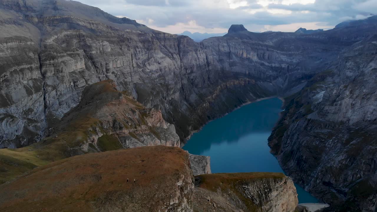A flyover above the cliffs overlooking lake Limmernsee in Glarus, Switzerland with the dark landscape at twilight