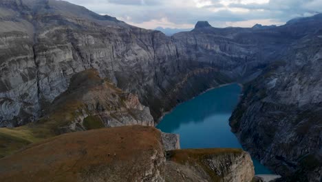 A-flyover-above-the-cliffs-overlooking-lake-Limmernsee-in-Glarus,-Switzerland-with-the-dark-landscape-at-twilight