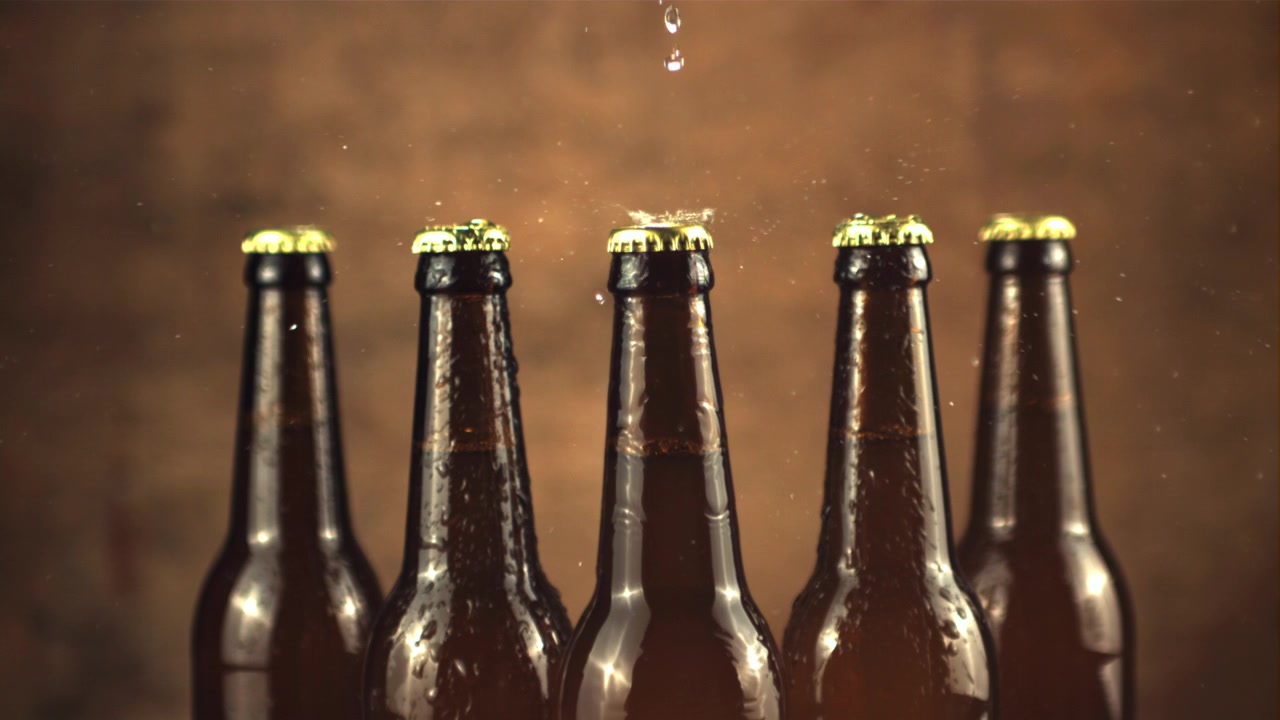 Gocce d'acqua al rallentatore che schizzano su bottiglie di birra fredda