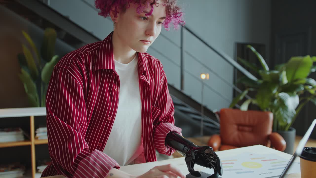 Female Employee with Prosthetic Arm Typing on Laptop at Office Desk
