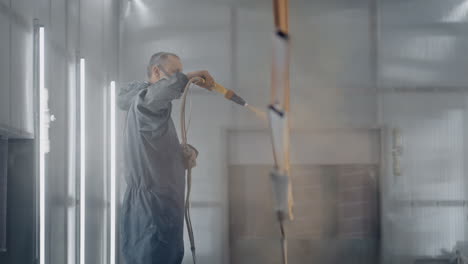 Un-Hombre-Con-Un-Respirador-Está-Pintando-Metal-Con-Un-Método-En-Polvo.-Producción-De-Estructuras-De-Acero-Y-Metal.-Taller-De-Pintura.-El-Pintor-Trabaja-Con-Una-Pistola-De-Pintura