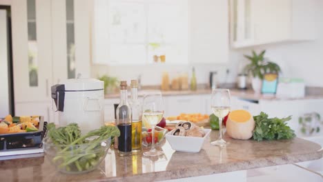 vegetables and glasses of white wine on countertop in kitchen