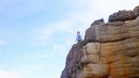 excursionista masculino de pie en la cima de una montaña rocosa 4k