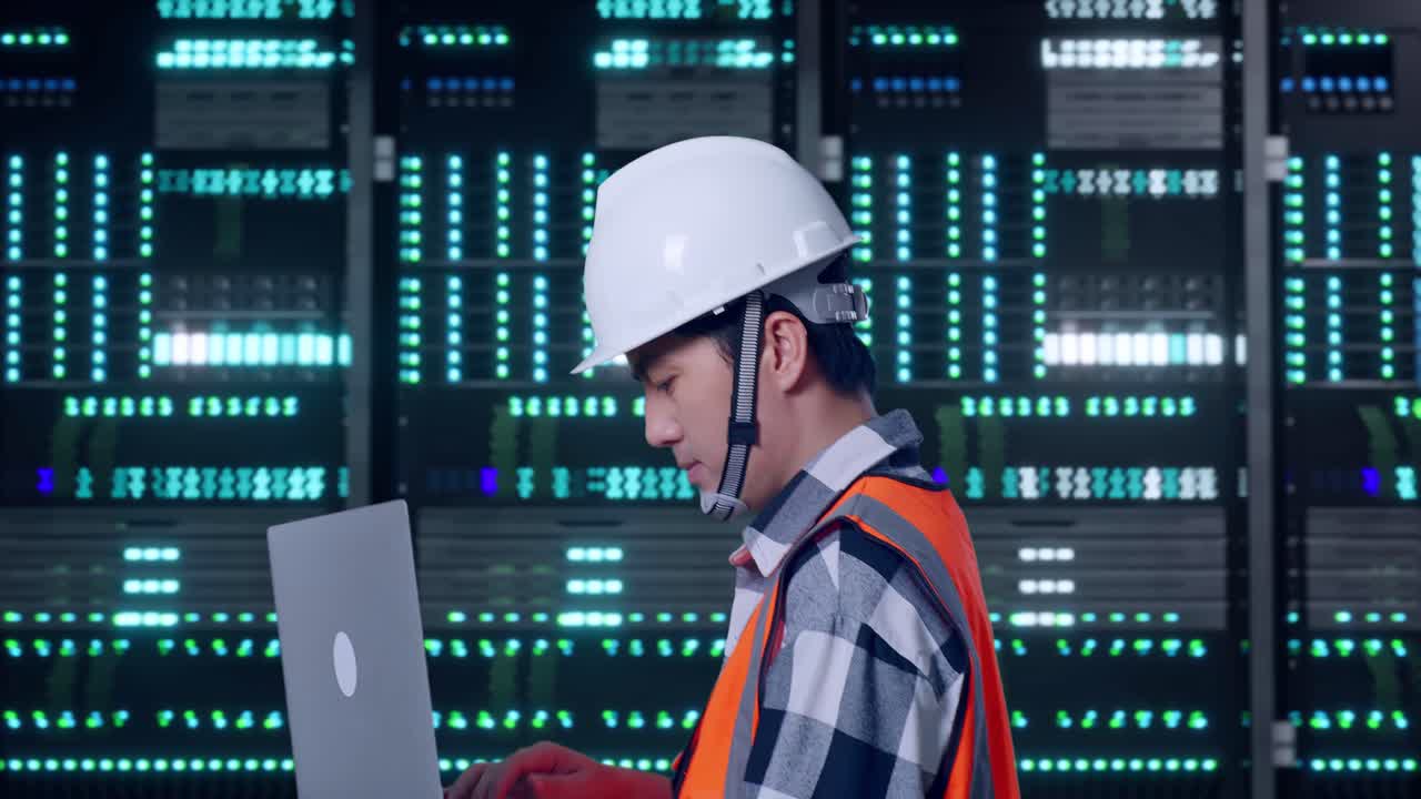 Side View of Asian Male Engineer Use Computer While Walking in Server Room Data Center