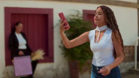 Young woman interacts with smartphone outdoors, taking selfies