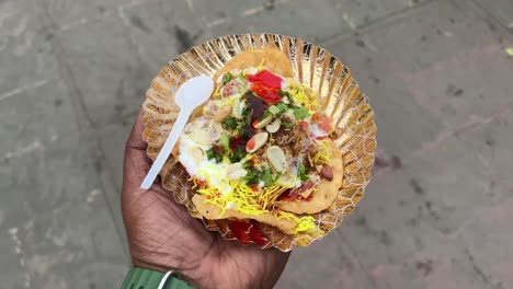 cinematic shot of papri chat garnished with onion, curd, peanuts and bhujia.