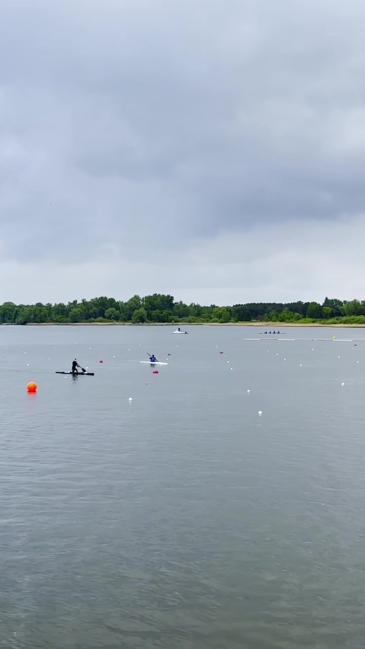 Kano sprintatleter træner på stille Beetzsee-vand ved siden af markerede racerbaner i Brandenburg, vertikalt statisk.