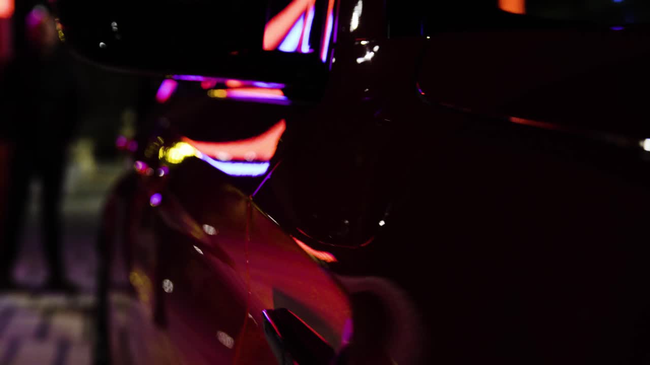 Primer plano detallado de los reflejos traseros de fibra de carbono en un coche deportivo rojo en la noche oscura de la ciudad, estático-1.