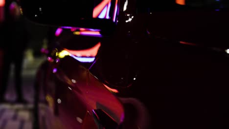 detalle closeup reflejos de fibra de carbono traseros en un coche deportivo rojo en la noche oscura en la ciudad de pie estático-1