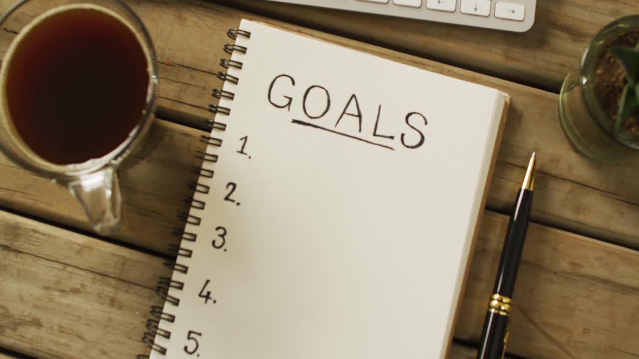 目標とコピースペース,木製の表面上のコーヒーとペンを持つノートブックのビデオ