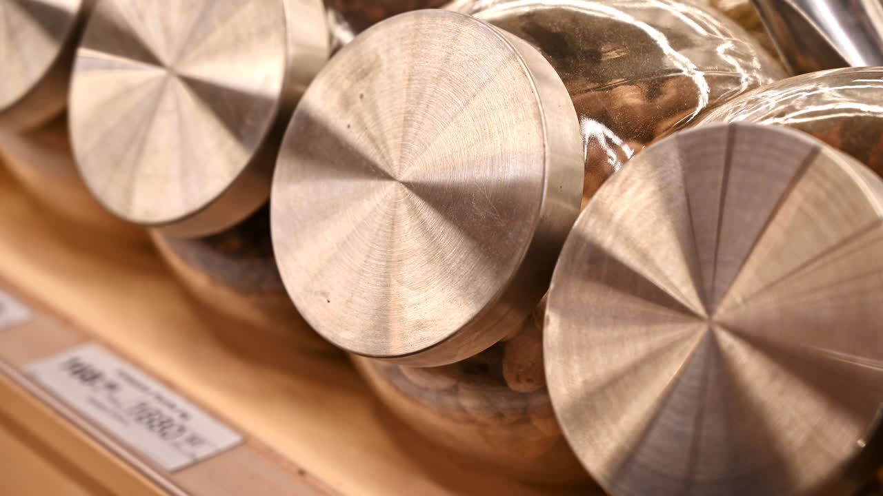 Man's hands unscrewing the lid of a jar with nutmegs and filling in another glass jar. Ecology idea