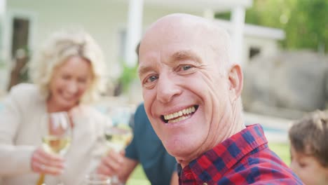 portrait of happy senior caucasian man having breakfast with family in garden