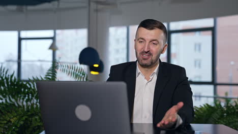 confident male entrepreneur chatting on laptop. man having business negotiations via internet. blurred office background.