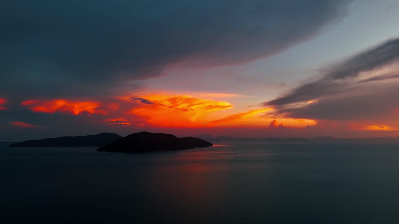 Flammend roter Sonnenuntergangshimmel über einer Insel an einem bewölkten Tag