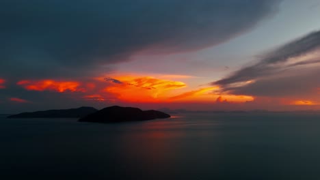 el cielo rojo ardiente del atardecer sobre una isla en un día nublado