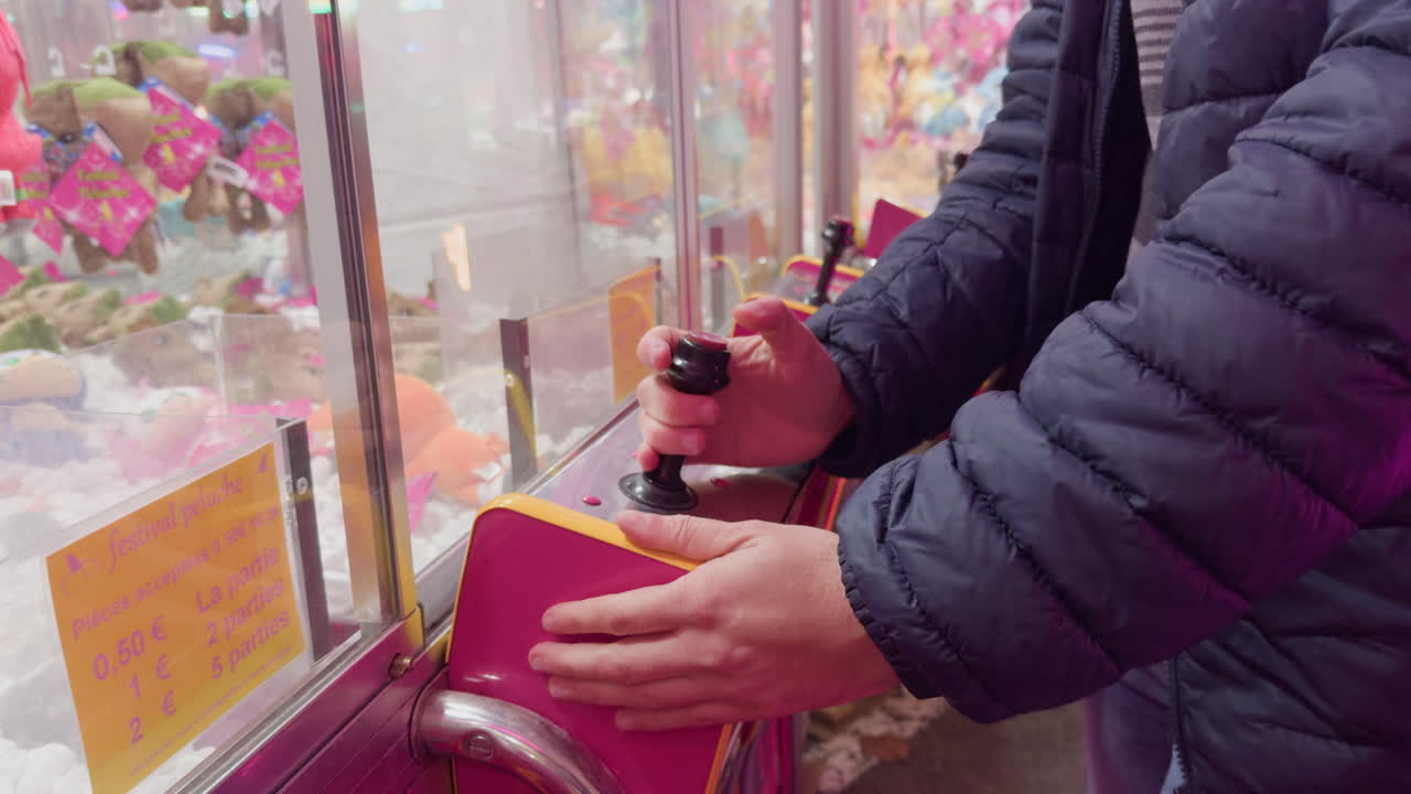 Man playfully using joystick on a claw machine at a French funfair in Montrichard Val de Cher