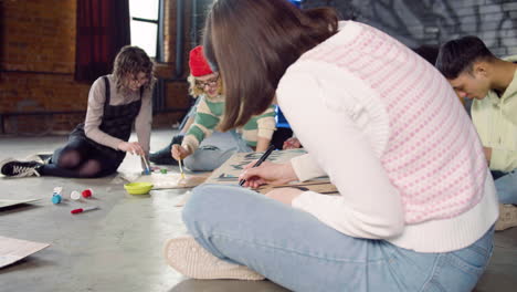 young environmental activists painting placards sitting on the floor