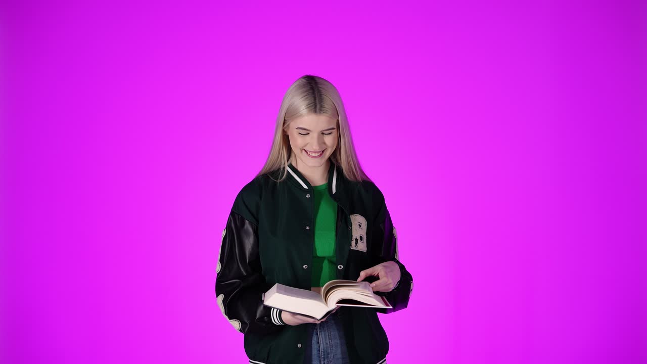 Ragazza carina che ride, guarda in camera e legge un grande libro, scatto in studio