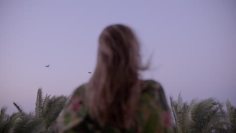 Mujer-Joven-En-Un-Balcón-Mirando-A-Lo-Lejos,-Observando-Los-Pájaros-Volando-Y-Disfrutando-Del-Viento-De-La-Tarde.