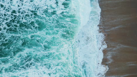 blue sea water crashing of sandy beach in slow motion. aerial view ocean waves.