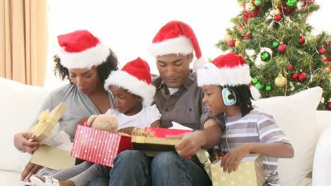 familia afroamericana abriendo regalos de navidad en el sofá