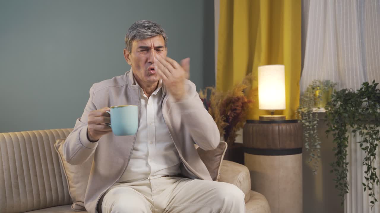 The old man's mouth is burning from the hot drink.