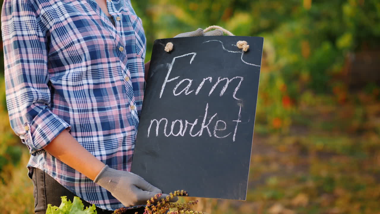 제철 야채와 함께 카운터 근처에 있는 농민 시장 표지판을 들고 있는 농부의 손
