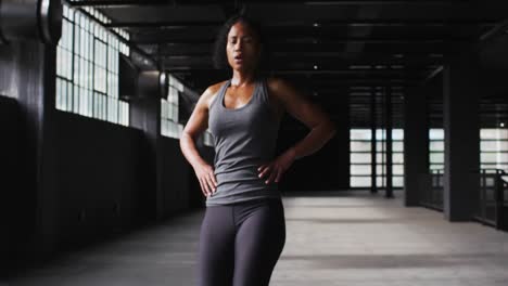 african american woman taking break during run in warehouse