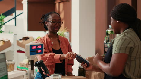 african american shopper paying with card at cash register