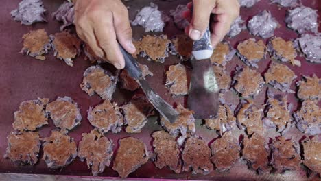 Vendedor-De-Comida-Cocinando-Y-Volteando-Panqueques-De-Arroz-Glutinoso-Tailandés-Hechos-De-Harina-De-Arroz-Glutinoso,-Almidón-De-Tapioca,-Carne-De-Coco-Rallada-Y-Leche-De-Coco,-En-Una-Plancha-Caliente