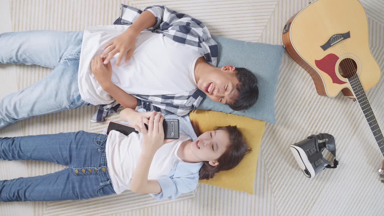 젊은 부부가 전화, 기타, vr 헤드으로 집에서 휴식을 취하고 있습니다.