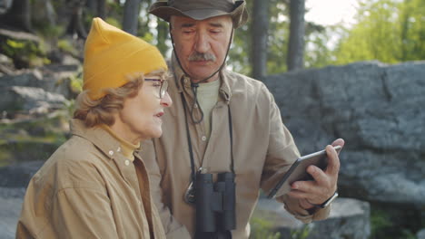 una pareja de ancianos haciendo senderismo y usando una tableta.