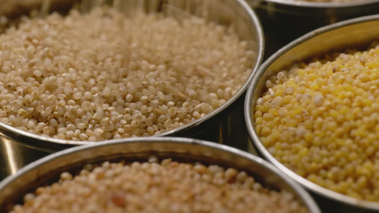 filling little millet in steel bowl with foxtail millet and barnyard millet for storage, 4k , close up, stable shot
