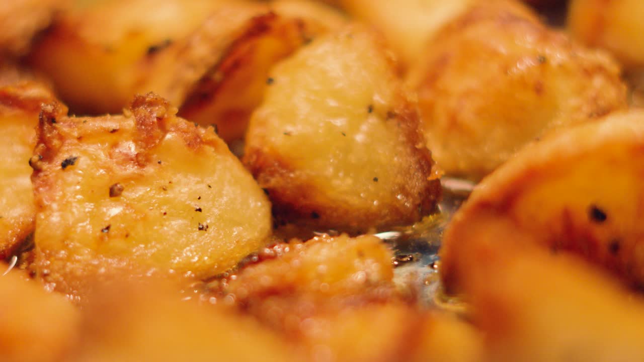 Close Up of Delicious Crispy Roast Potatoes with Oil Gently Bubbling Underneath. Classic Sunday British Lunch Dinner