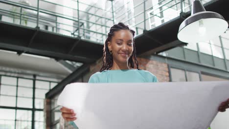 Glückliche-Afroamerikanische-Architektin,-Die-Sich-Im-Büro-Architektonische-Pläne-Ansieht