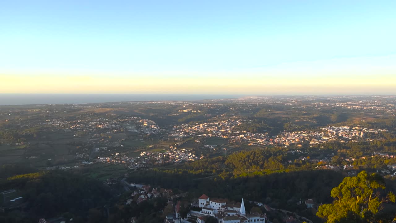 Panorama dorato al tramonto dal Castello moresco di Sintra con vista su foreste ondulate, verdi colline e case bianche con tetti rossi in tutto il Portogallo