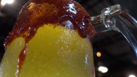disparo de rotación lenta de una bebida gaseosa naranja en un vaso con salsas bordeadas alrededor del vaso