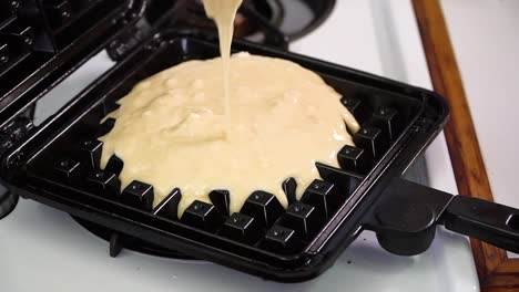 slow motion thick batter poured into stovetop belgian waffle iron, bubbles and spreads, lid closes, 60fps