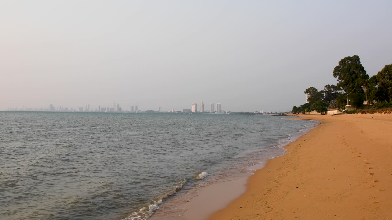 Bellissime onde calme lungo la spiaggia di Bangsaray a Pattaya, Thailandia, con edifici della città all'orizzonte sullo sfondo