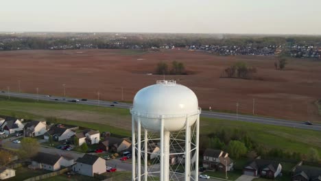 Aerial-vertigo-shot-of-water-tower,-revealing-farm-land-in-the-background