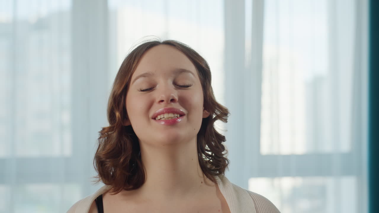 Donna sorridente che registra video con illuminazione calda, vlogger che coinvolge gli spettatori con espressioni accattivanti, donna gioiosa che crea contenuti in un appartamento accogliente con fare cordiale