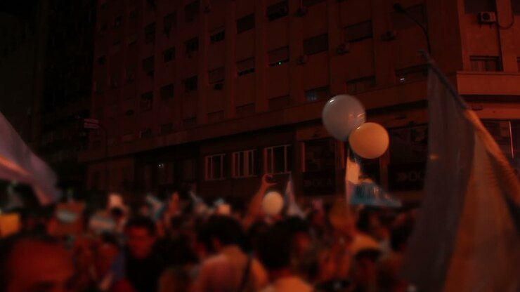 Folla sfocata che sventola bandiere argentine durante una celebrazione notturna