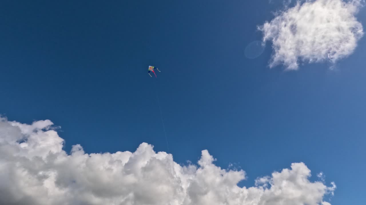 Le persone si radunano in un parco per far volare aquiloni colorati. Bambini e adulti corrono sull'erba mentre gli aquiloni si librano in aria. Il sole splende e le nuvole passano lentamente